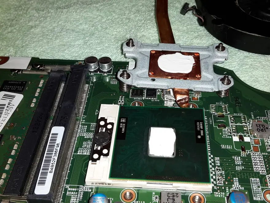 Placa de bază a unui laptop, cu procesorul și suportul de radiator demontate, în service-ul TechTeam din Pitești