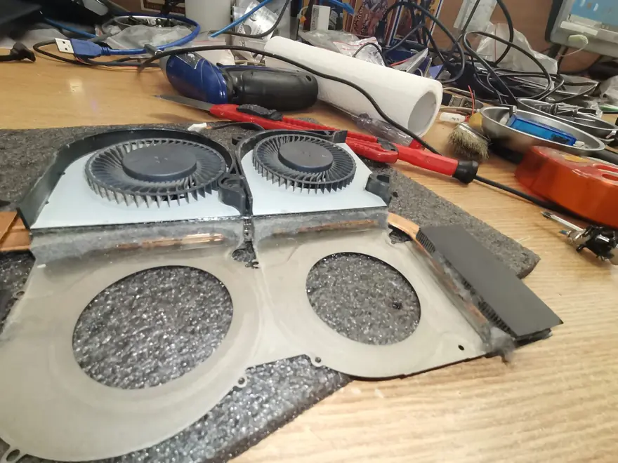 Două radiatoare de laptop scoase la curățare, cu stratul gros de praf înfundat între lamele, pe bancul din atelierul TechTeam Pitești